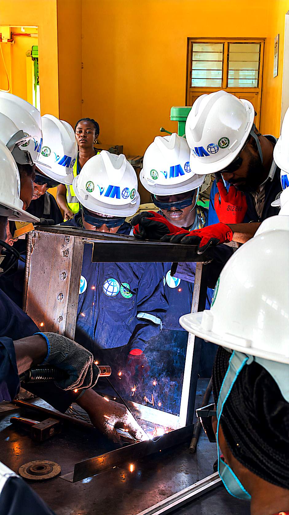 Close-up welding on a fabricated frame with cohort observing